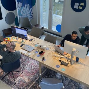 Groepjes mensen rondom computers in overleg