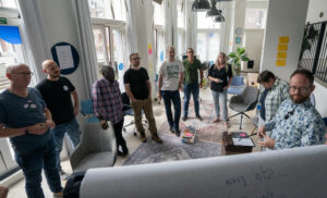 Een groepje medewerkers van TrailBlazers rondom een flipover tijdens een TrailBlazers-kwartaalmeeting op 20/8/2024.