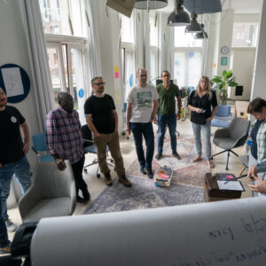 Een groepje medewerkers van TrailBlazers staand rondom een flipover tijdens een TrailBlazers-kwartaalmeeting op 20/8/2024.