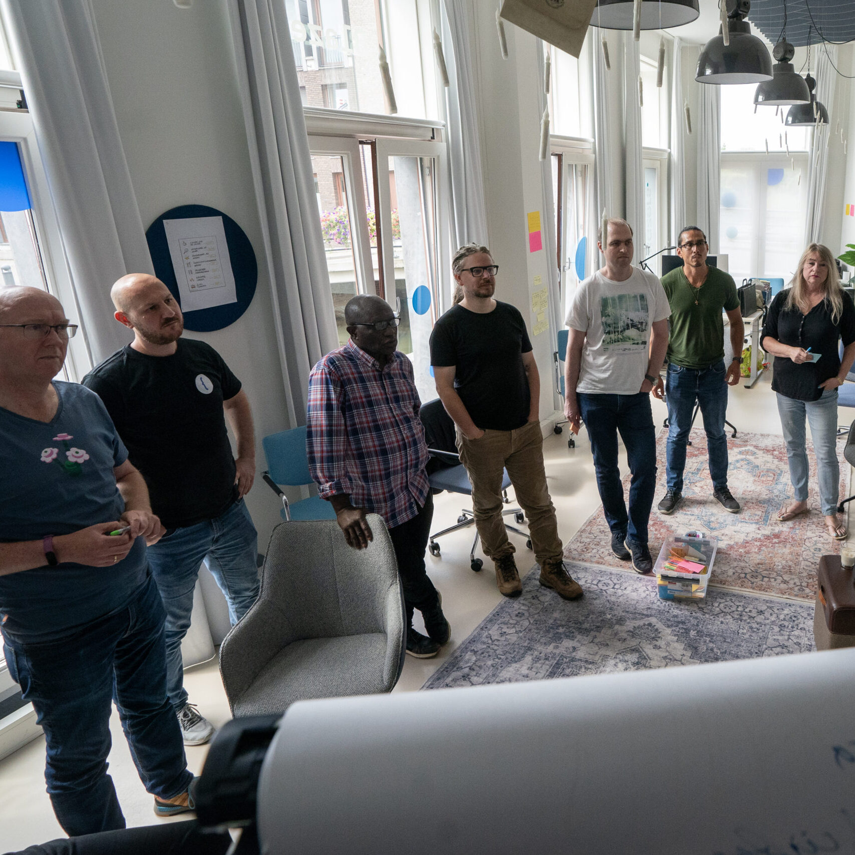Een groepje medewerkers van TrailBlazers staand rondom een flipover tijdens een TrailBlazers-kwartaalmeeting op 20/8/2024.