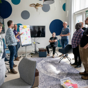Een groepje medewerkers van TrailBlazers staand rondom een flipover tijdens een TrailBlazers-kwartaalmeeting op 20/8/2024.